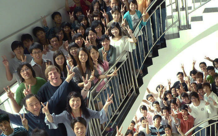 The animation staff of the TW3 facility in China packed onto a spiral staircase, waving at the camera.
