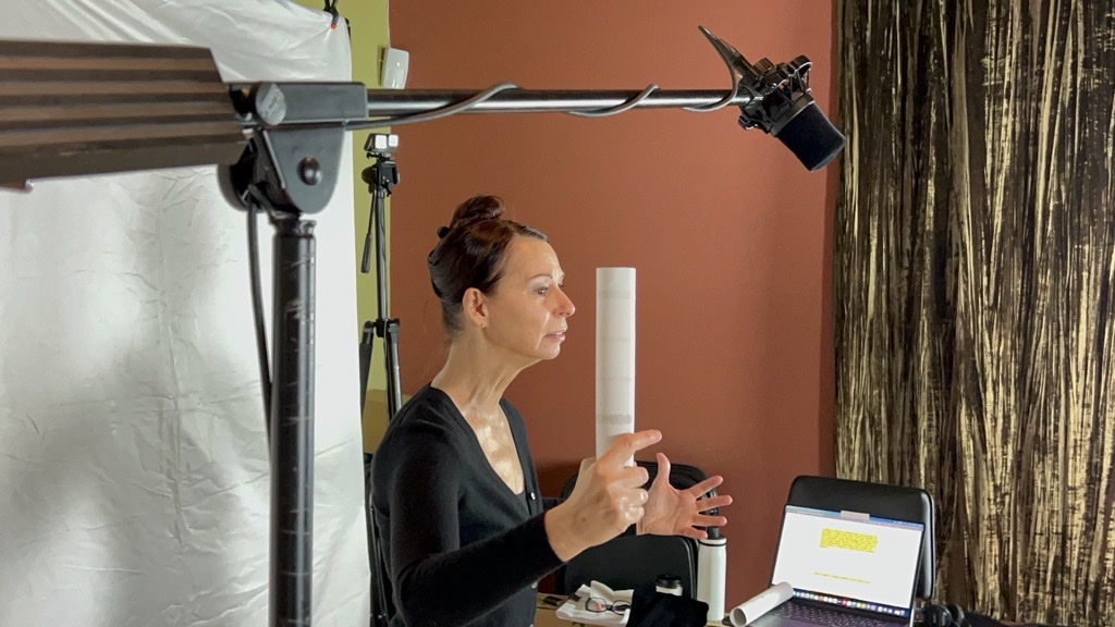 A presenter works to camera on the Merry shoot, boom mic overhead and a softbox to one side.