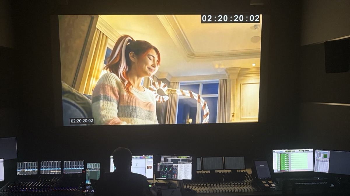 A scene from Merry on the dub-stage screen above a full mixing console.