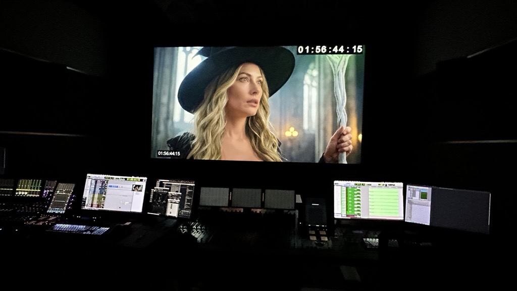 Esmeralda on the dub-stage screen, timecode running, above a full mixing console.