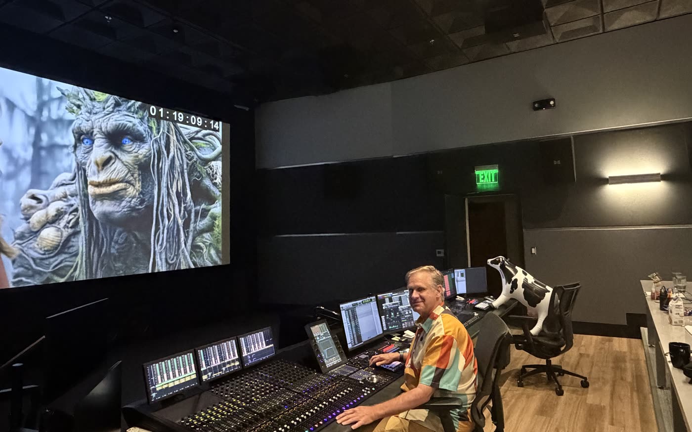 A mix engineer at the console on the dub stage, Swampy on the screen above with timecode running.