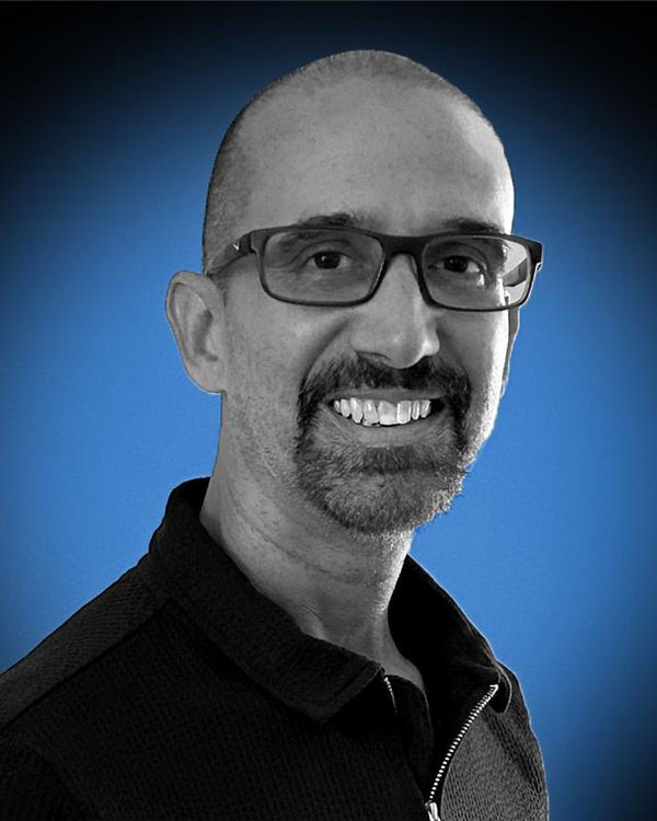 Duane Vaiani, smiling against a blue studio backdrop.