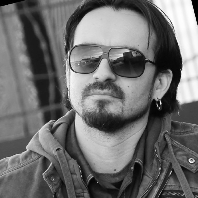 Mauricio Aguilera, in sunglasses and a work jacket, photographed in black and white.