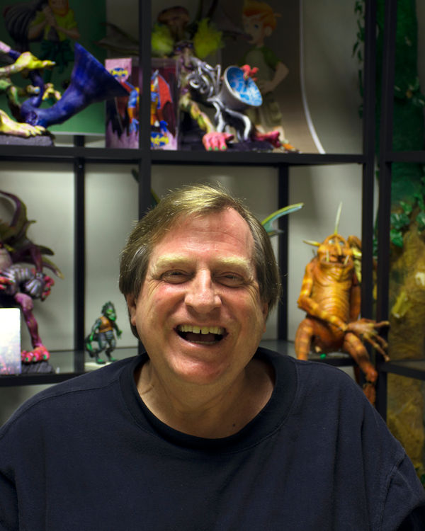 Tom Walsh, laughing in front of shelves of original TW3 character maquettes.