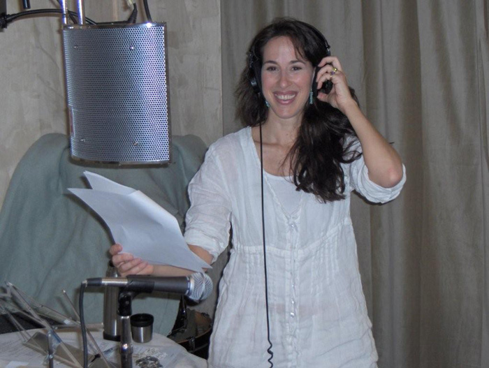 An actor records dialogue at a studio microphone, script in hand.