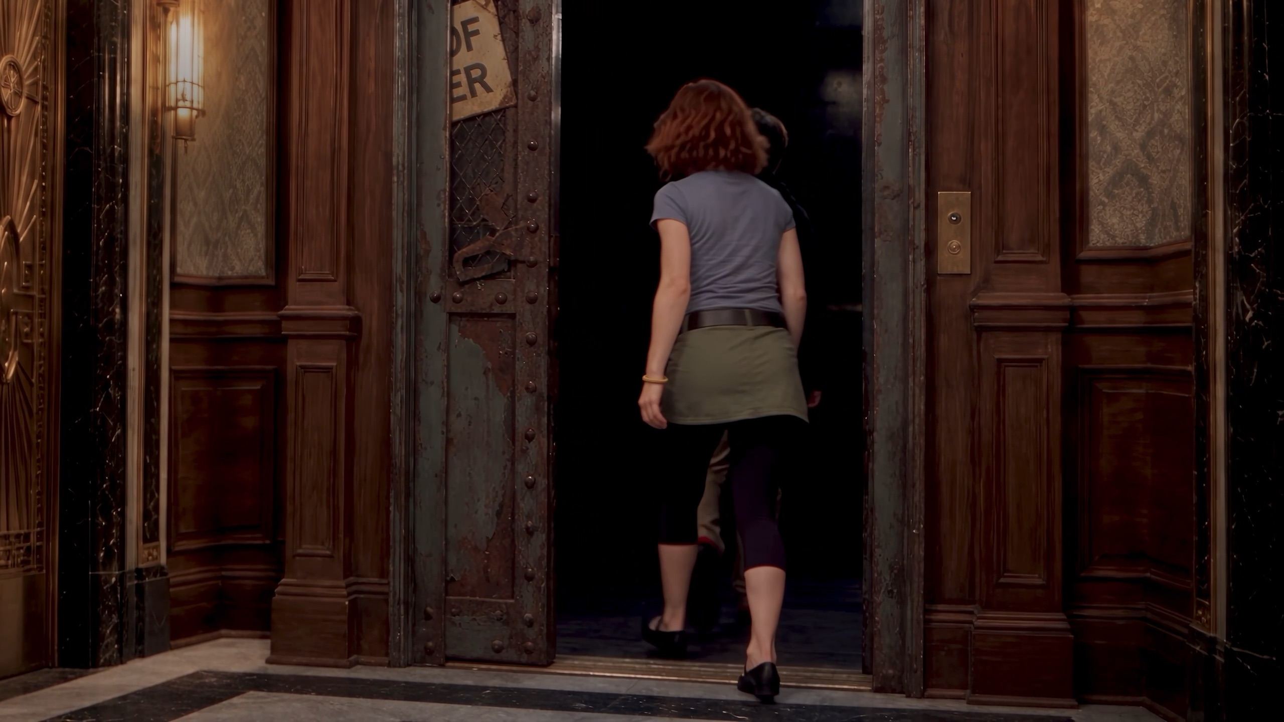 Two teenagers force open a rusted freight elevator door marked Out of Order and step into the dark.